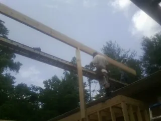 Carpenter setting a ridge beam over a new addition frame — Ice Dam Removal by Roofing Brothers in Glouster