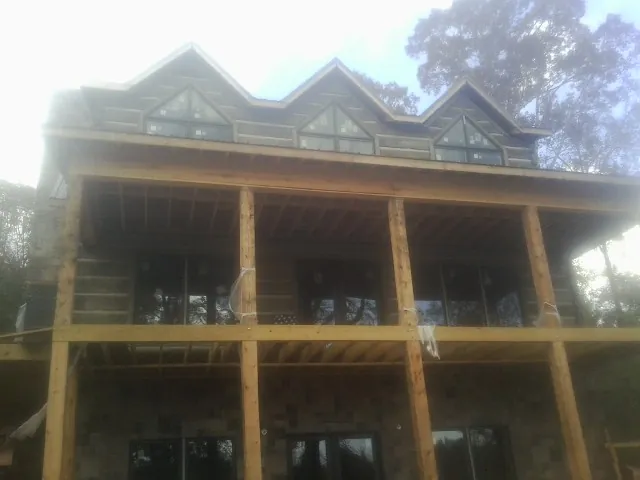 Dormers and porch framing on a large log home under construction — Roof Coating work by our crew in Glouster