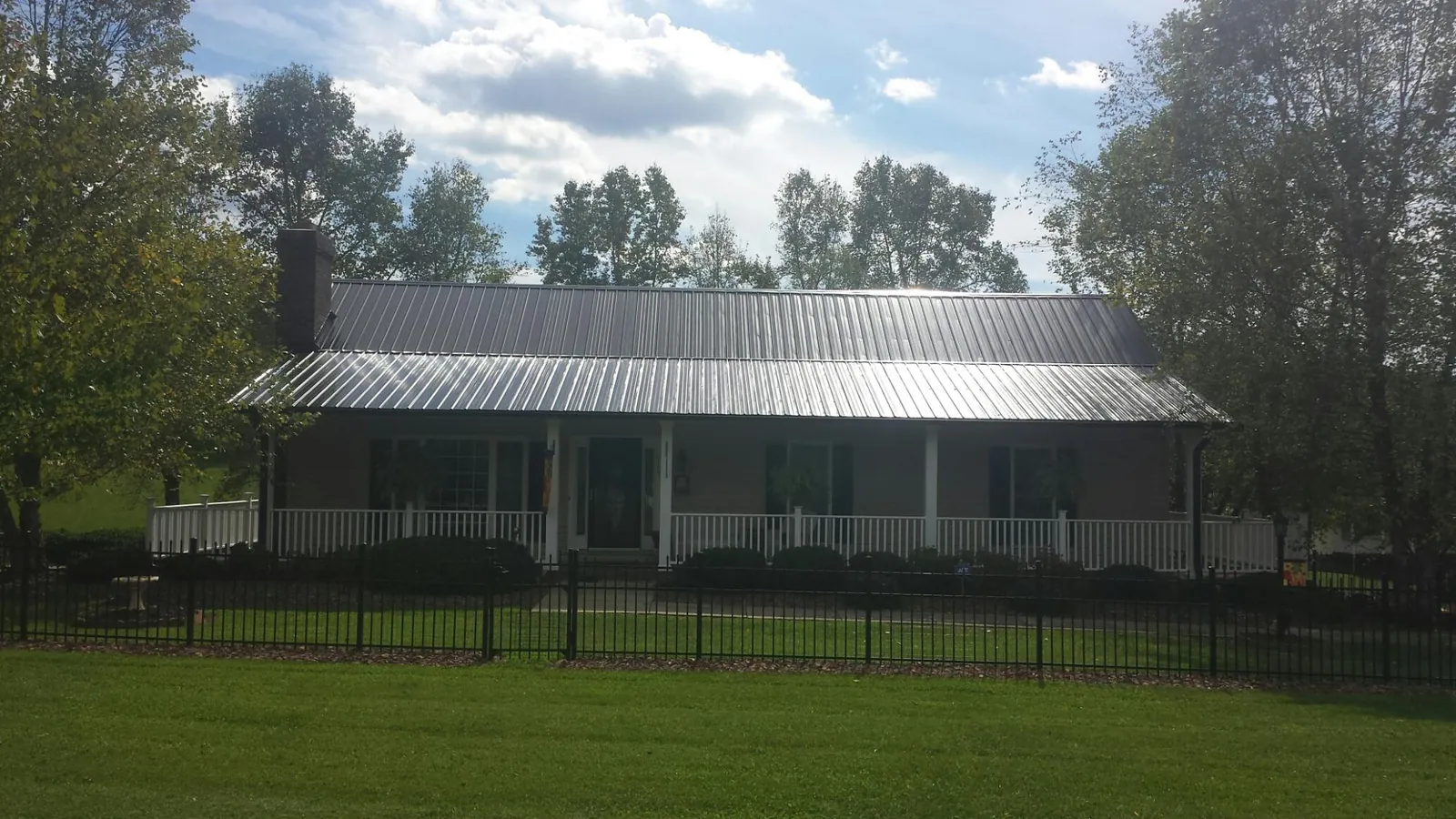 Gray metal roof on a brick ranch with a full width front porch — Gutter Guard Installation work by our crew in Glouster
