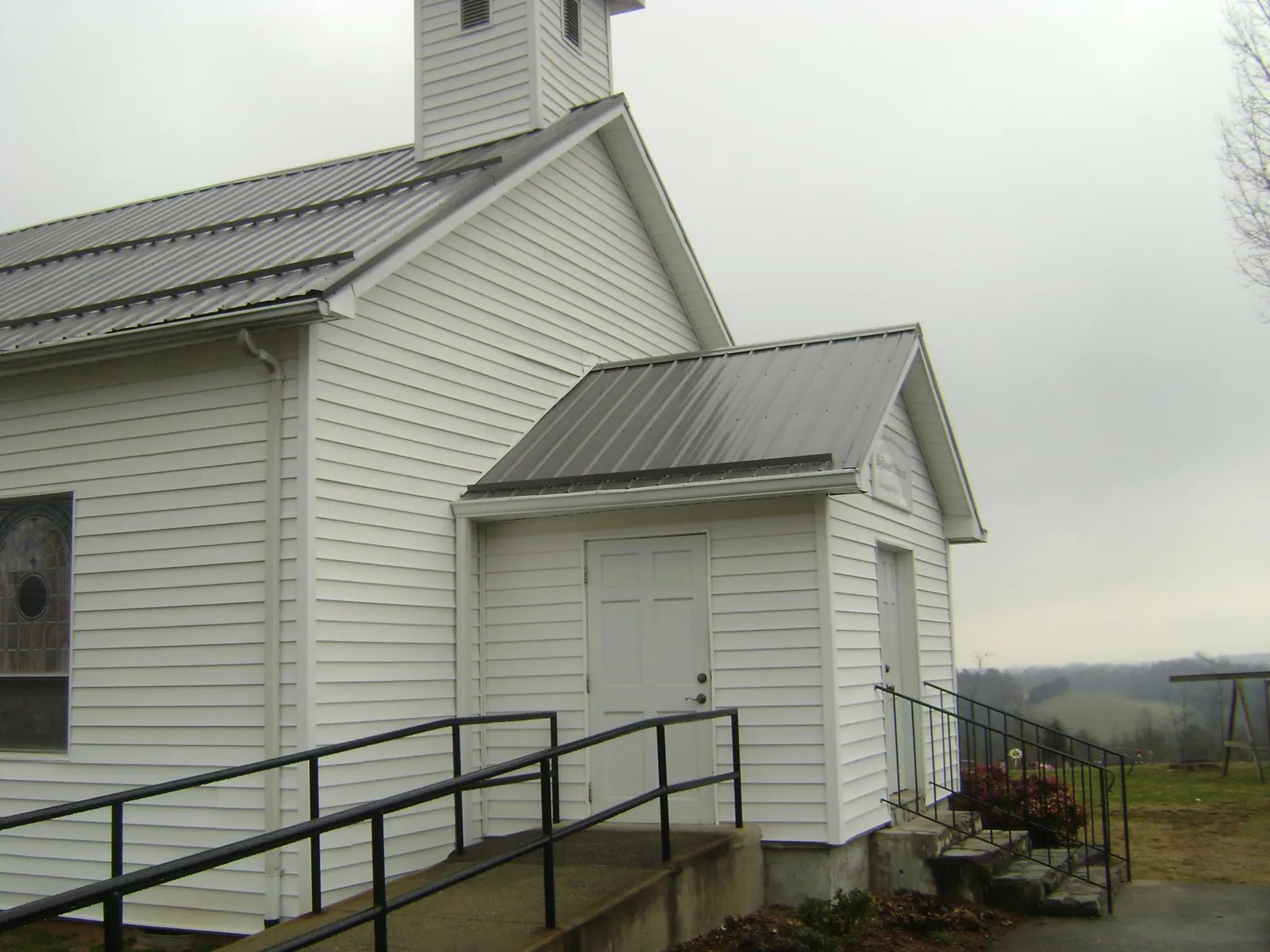Gray metal roof on a white clapboard church with a steeple in Glouster