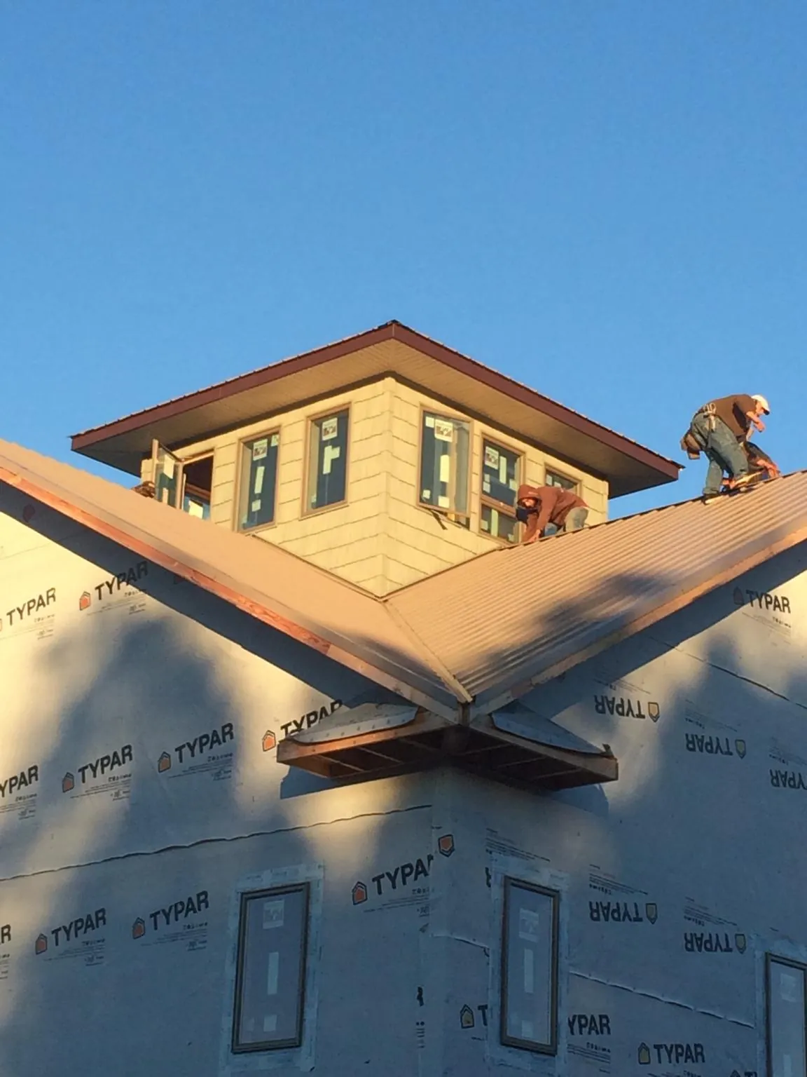 Roofers working around a rooftop cupola on a new metal roof at sunset — Roof Waterproofing in Glouster by Roofing Brothers
